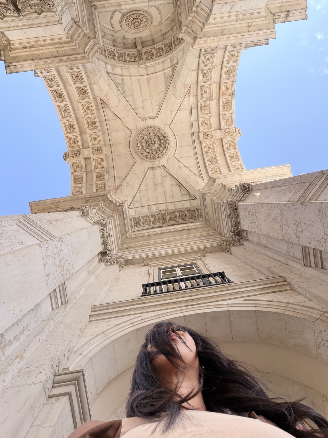 Jazmin beneath the ornate stone arch in Lisbon, Portugal